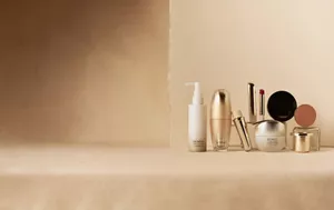 SENSAI Sustainable Care product lineup on a beige surface against a neutral background